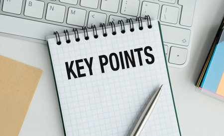 A spiral notebook with a pen on it and the words Key Points written on it. The notebook is on a desk...