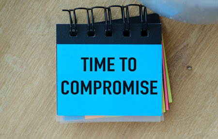 A blue notebook with a yellow, green, and red strip on it that says Time to Compromise.