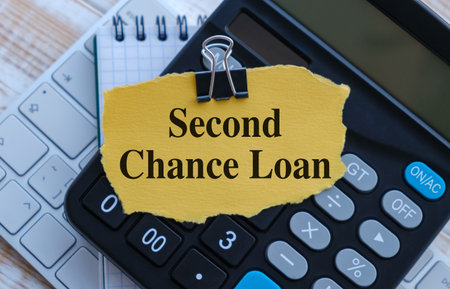 A calculator is on a table with a piece of paper that says Second Chance Loan on it, business...