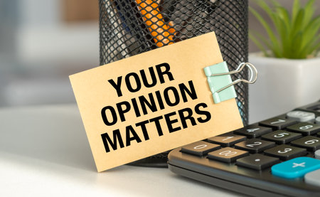 A small sign that says Your Opinion Matters is sitting on top of a calculator. The sign is clipped to the calculator with a paper clipの写真素材
