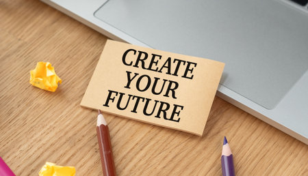 A sign that says Create Your Future is on a desk with a laptopの写真素材