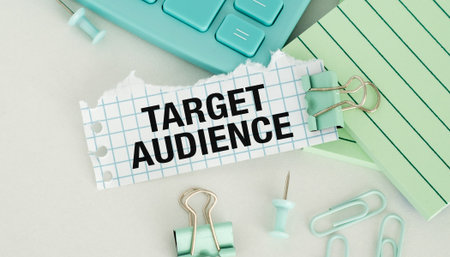 A piece of paper with the word Target Audience written on it, along with a pair of paper clips