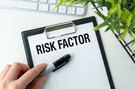 A doctor holding marker on clipboard with the word Risk Factor written on it.