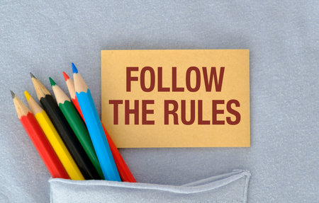 A sign that says Follow The Rules is on top of a pile of colored pencils, Business Conceptの写真素材