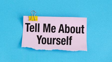 A piece of paper with a clip holding it in place. The paper says Tell me About Yourself.の写真素材
