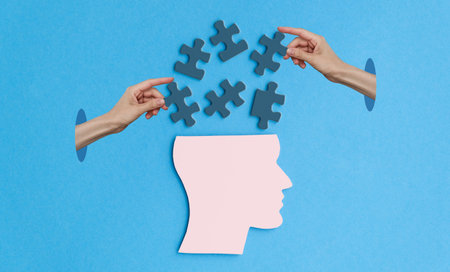 A puzzle piece is shown with a person's hand holding it. The image is a representation of the idea that solving a puzzle requires teamwork and collaboration. The blue background adds a calmingの写真素材