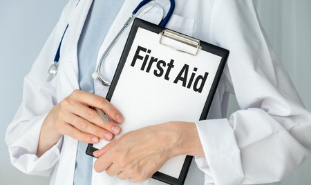 First AID text message on paper card in hands Doctor with stethoscope on white backgroundの写真素材