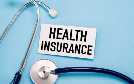 A stethoscope is next to a white card that says Health Insurance. The stethoscope is a medical instrument used to listen to the soundsの写真素材