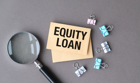 A magnifying glass is on top of a piece of paper that says Equity Loan. The paper is on a table with a bunch of clipsの写真素材