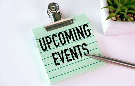 A green clipboard with the word Upcoming Events written on it. A pen is placed on top of the clipboardの写真素材