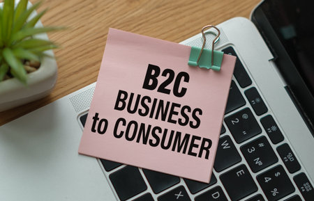 B2C Business to Consumer inscription on pink sticky note lying on laptop on office deskの写真素材