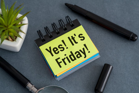 Yes It's Friday inscription on open notebook with black marker and magnifying glass with houseplant on gray backgroundの写真素材