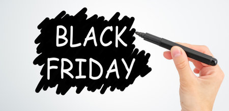 A hand is writing the word Black Friday on a white background. Concept of a special day for shopping and saving moneyの写真素材