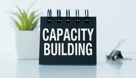 Notepad with text CAPACITY BUILDING on a white background, paper clips, calculator.の写真素材