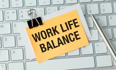 Work Life Balance Text on a yellow sticky note with a clip on a keyboard with a penの写真素材