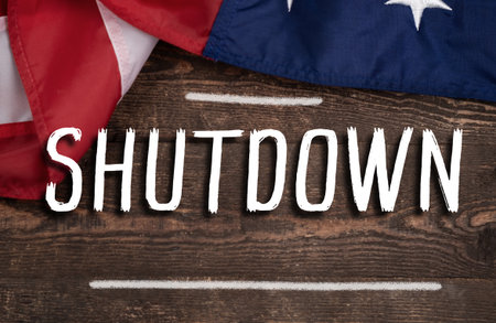 A flag is on a wooden surface with the word Shutdown written below it. concept of american politics crisis, government shutdown and bipartisan conflictの写真素材