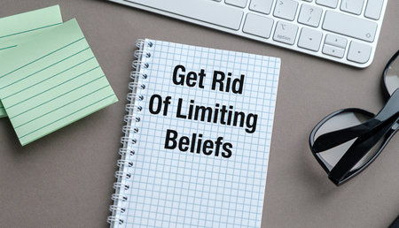 A notebook with the words Get Rid of Limiting Beliefs written on it. The notebook is sitting on a...