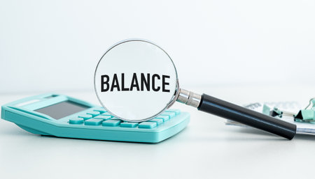 A calculator and a magnifying glass with the word balance written on it. Concept of Balance and the importance of paying attention to detailsの写真素材