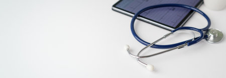 A stethoscope is on a table next to a tablet. The stethoscope is blue and silverの写真素材