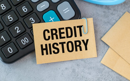 A calculator sits on a table with a piece of paper that says Credit History on itの写真素材