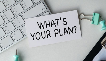 A white piece of paper with the words What's Your Plan written on it. The paper is sitting on a desk next to a keyboardの写真素材