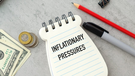A notebook of money and. coins with a paper notebook that says Inflationary Pressuresの写真素材