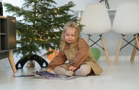 little girl 5 years old in dress, reading book with pleasure and looking at pictures with interest, child at home. child's fantasy, happy childhood.の写真素材