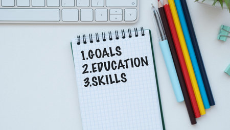 Goal, Education, Skills text on open notebook with colored pencils and a keyboard on a white table
