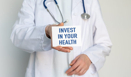 Doctor holding a card with INVEST IN YOUR HEALTH text for medical insurance, healthcare prevention,...