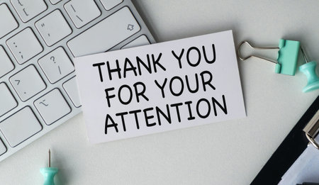 THANK YOU FOR YOUR ATTENTION message on a white card placed on an office desk with a laptop keyboard...