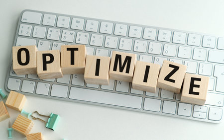 OPTIMIZE word on wooden blocks placed on a computer keyboard, representing business efficiency,...