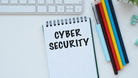CYBER SECURITY text in a notebook on a desk with a computer keyboard and stationery, representing...