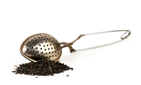 A bunch of black tea leaves and a teaspoon on a white background. Isolatedの写真素材