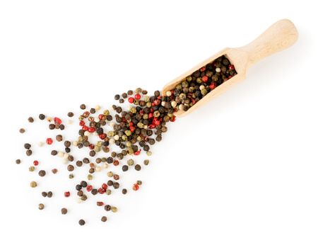 A mixture of pepper peas poured from a wooden spoon on a white background, isolated.