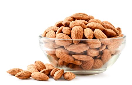 Almonds in a glass plate and scattered on a white background. Isolatedの写真素材