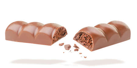 Porous chocolate is broken and flies close-up on a white background. Isolated