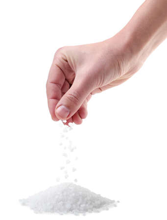 Hand pours salt crystals on a pile close-up on a white background. Isolatedの写真素材