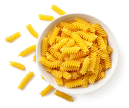 Raw spiral pasta in a plate close-up on a white background, isolated. The view from topの写真素材