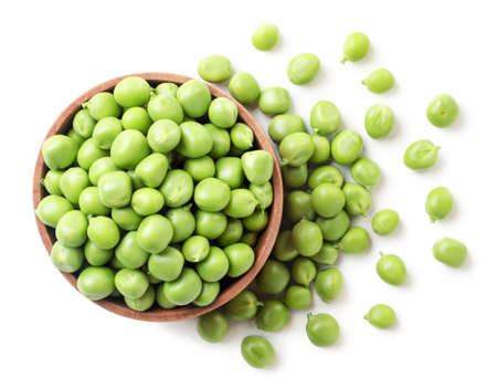 Green peas in a wooden plate and sprinkled close-up on a white background. Top view.の写真素材