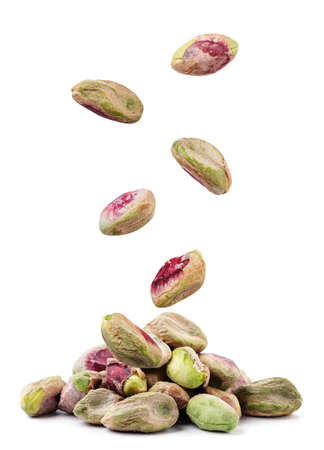 Peeled pistachios fall on a pile close-up on a white background. Isolatedの写真素材