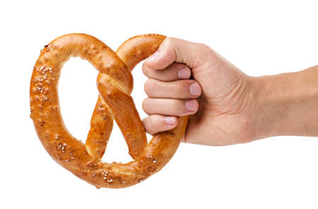 Pretzel in hand close-up on white background, oktoberfest snack. Isolatedの写真素材