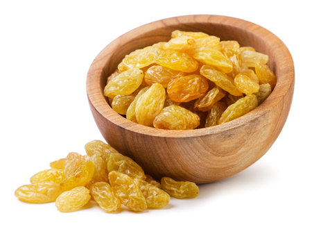 Yellow raisins spilled from a wooden plate close-up on a white background. isolatedの写真素材