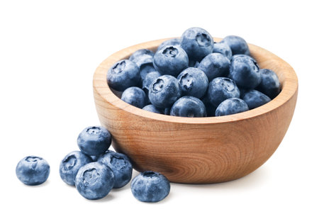 Blueberries in a wooden plate and scattered close-up on a white background. isolatedの写真素材