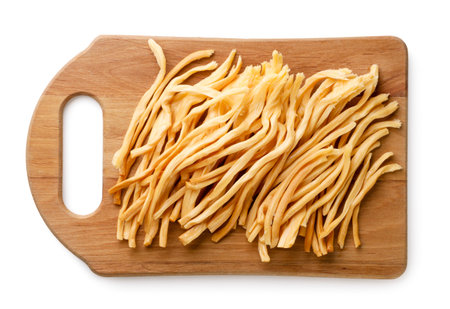 Pieces of smoked cheese on a kitchen board close-up on a white background. Top view. Chechel cheese...