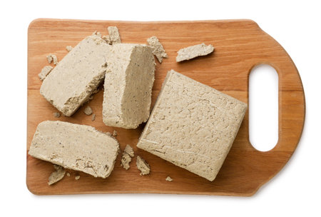 Halva and pieces on a wooden board close-up on a white background. Top view
