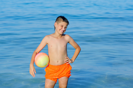 boy playing ball in a beautiful tropical sea. happiness, joy, splashing, teenの写真素材
