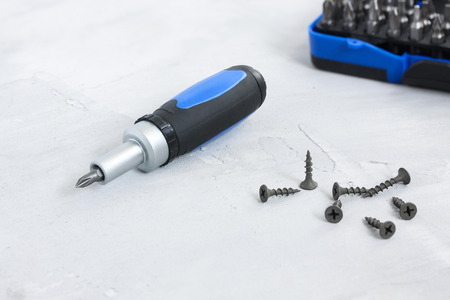 Tool set screwdriver with different nozzles and screws on gray concrete backgroundの写真素材