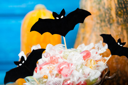 Halloween paper bats, pumpkins and candy bucket on blue backround