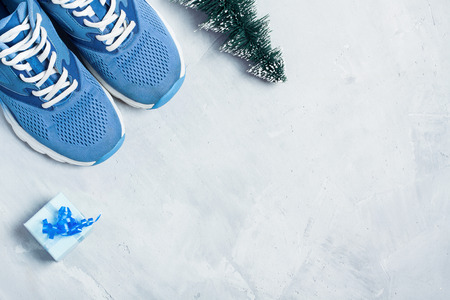 Christmas sport flat lay composition with shoes, christmas tree and blue gift box on gray concrete background. Concept ?hristmas special for healthy lifestyle and sport.の写真素材