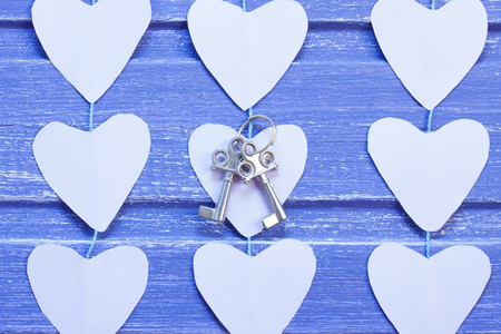 Paper hearts and silver keys on purple wooden background. Horizontal orientation, Close-
up. Valentine background.の写真素材